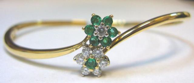 JCSA901: Hinged bangle bracelet with emeralds and diamonds.  The by-pass design bracelet contains 7 round emeralds (.30cts) and 7 round diamonds (.40cts) all prong set.  This bracelet matches style number 910-20-939 and is 14kt yellow gold.