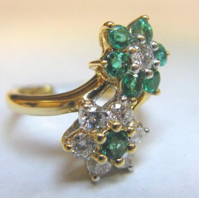 JCSA900: Classic by-pass, floral design, emerald and diamond ring.  The ring contains 7 round diamonds (.40cts) and 7 round emeralds (.30cts).  All of the stones are prong set in a 14kt yellow gold mounting.